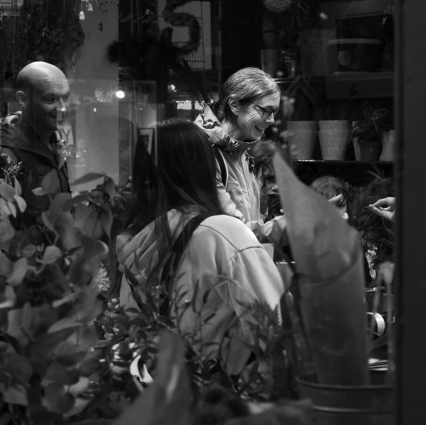 Black-and-white shoppers browsing among plants at a flower stall